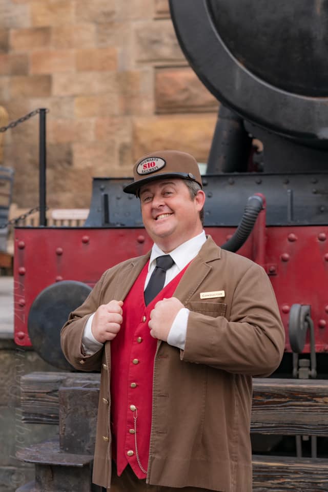 A conductor in front of the Hogwarts Express