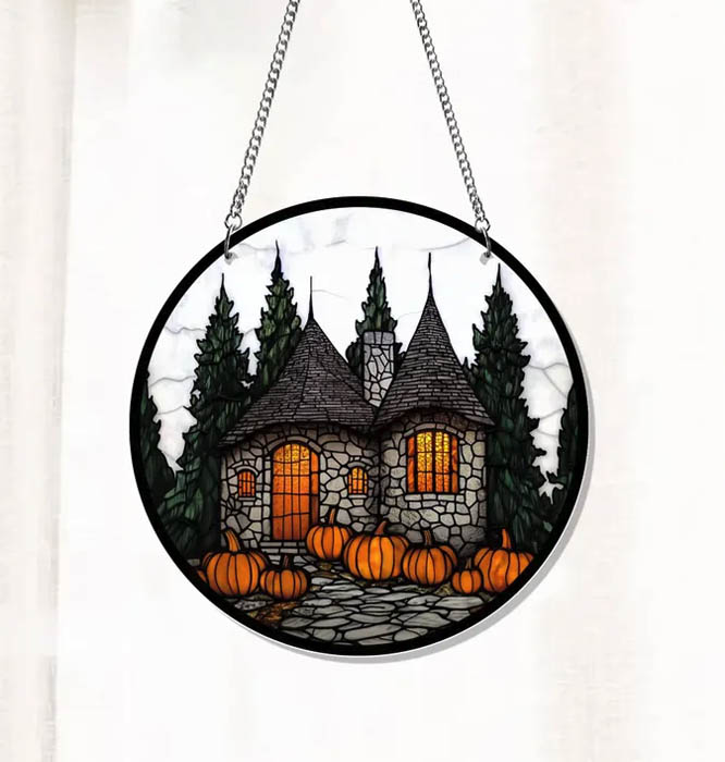 Round, acrylic sun catcher of a cabin and pumpkins